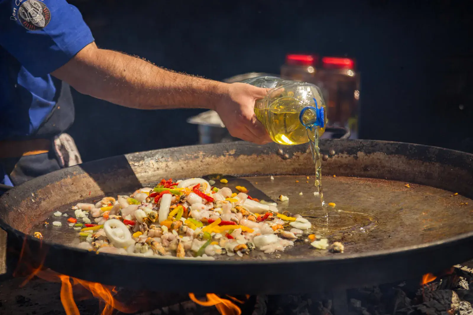 Aceite cayendo sobre la paellera al fuego para empezar el sofrito